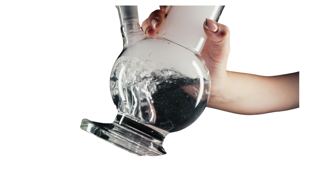A person's hand holds a glass bong filled with water, creating splashes as it's tilted to pour out some liquid.